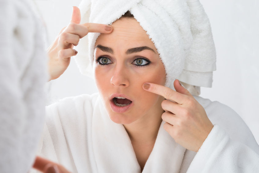 39435265 – close-up of worried woman looking at pimple on face in mirror